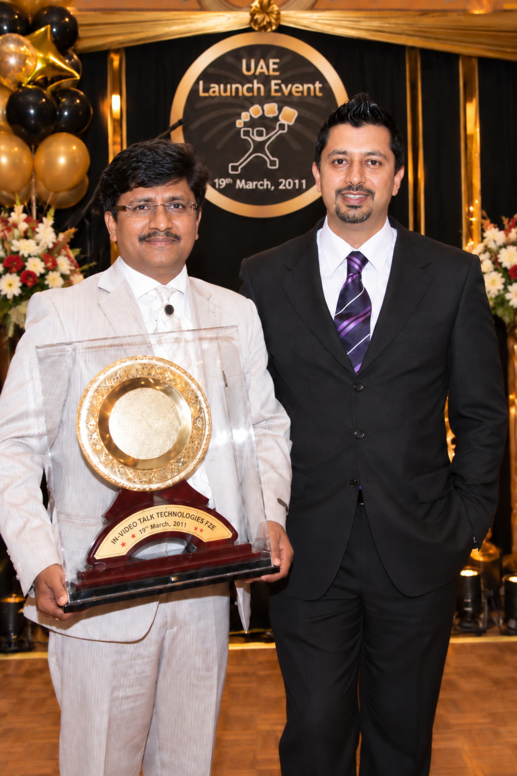 Sonu Sandhu with a colleague holding the trophy in front of the UAE Launch Event, 19 March 2011 backdrop